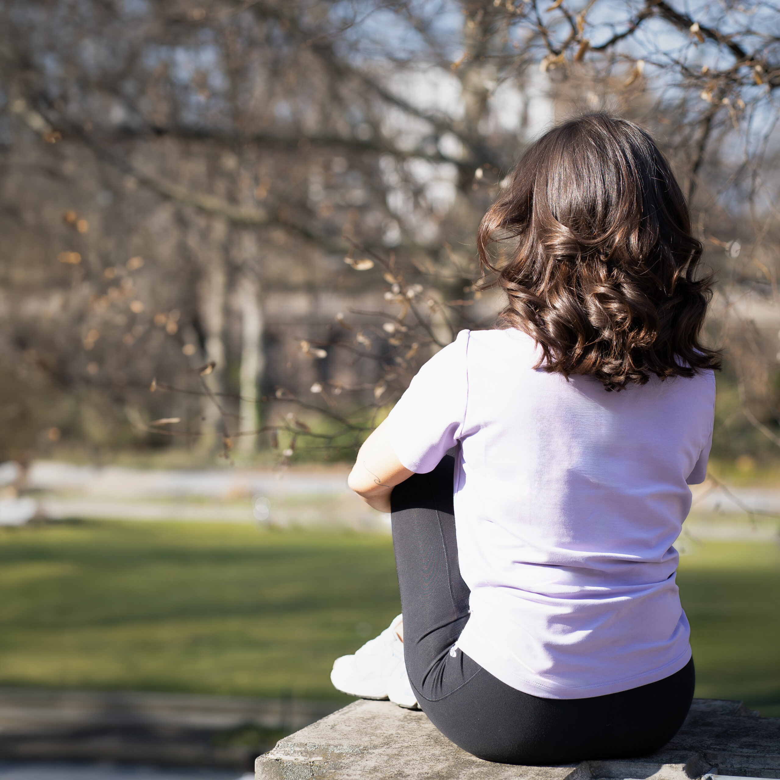 Frau sitzt nachdenklich im Park in Berlin – Moment der Selbstreflexion im Life Coaching bei Dee-Fit